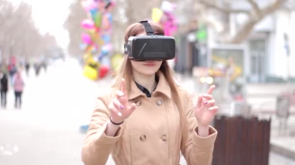 Happy young woman wearing cyberspace technology virtual reality vr headset glasses in beige outwear coat having fun outside in the street - Footage, Video