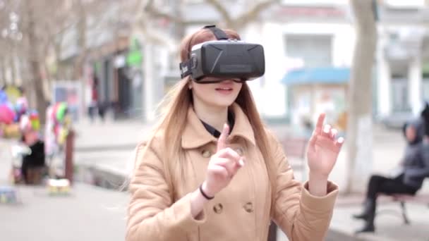 Glückliches Mädchen mit Virtual-Reality-Headset Cyberspace-Technologie Brille, die Spaß beim Spielen draußen auf der Straße in beigem Mantel hat - Filmmaterial, Video
