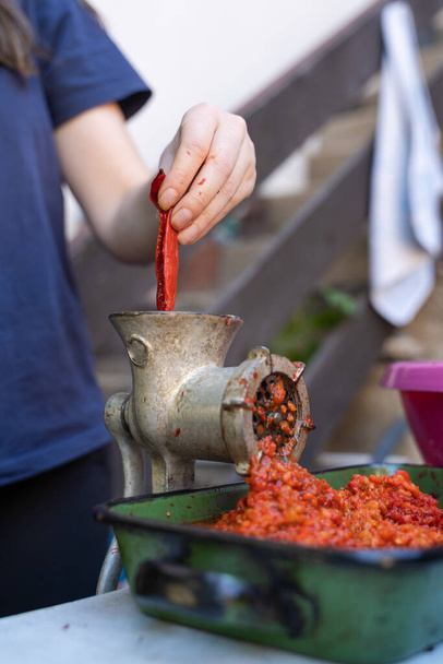 Close-up outdoor op vrouwelijke hand op molen voor groenten bereiden paprika gebakken rode peper voor ajvar nationale schotel in balkan - gezonde biologische voeding concept - Foto, afbeelding