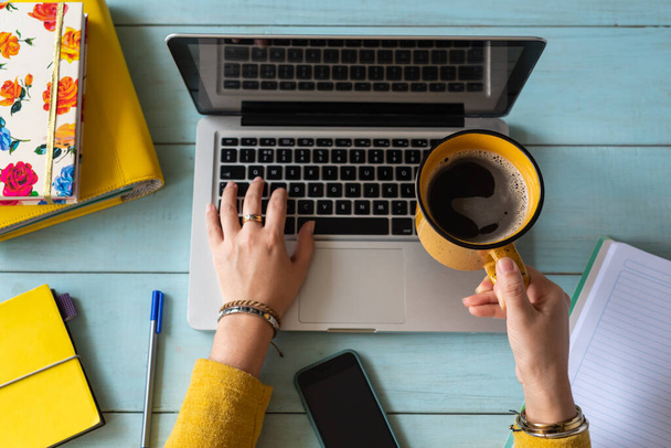 El enfoque selectivo de la mujer trabaja en su computadora portátil mientras sostiene una taza de café. Trabajo en casa concepto - Foto, Imagen