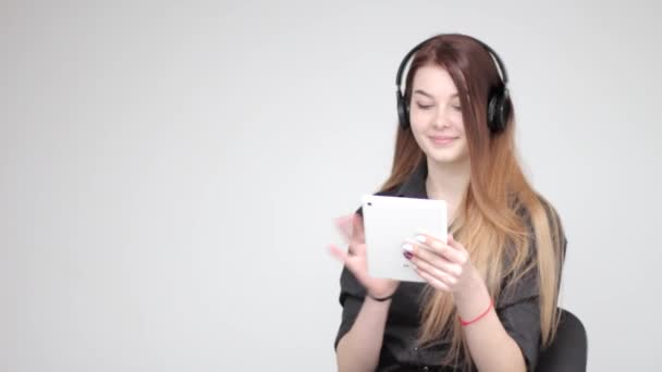 Νεαρή όμορφη γυναίκα που χρησιμοποιεί λευκό tablet ακούει μουσική σε ασύρματα ακουστικά - Πλάνα, βίντεο