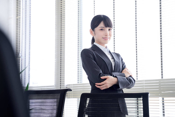 事務所の窓のそばに立つ日本人女性 - 写真・画像