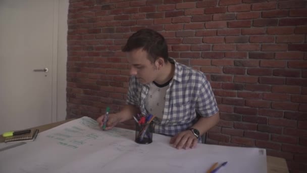 Confident young attractive concentrated man in plaid shirt working on business project thinking sitting by wooden table - Materiał filmowy, wideo