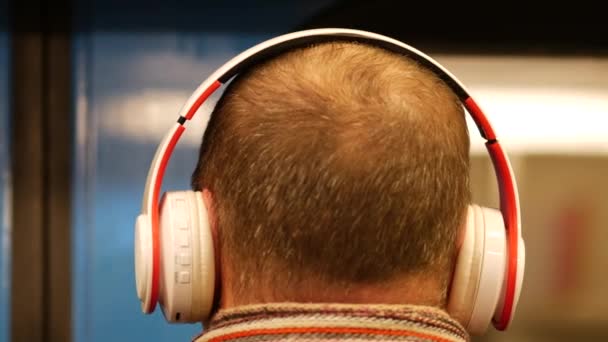 Homme méconnaissable avec écouteurs monte métro. La tête d'un homme aux cheveux courts - Séquence, vidéo