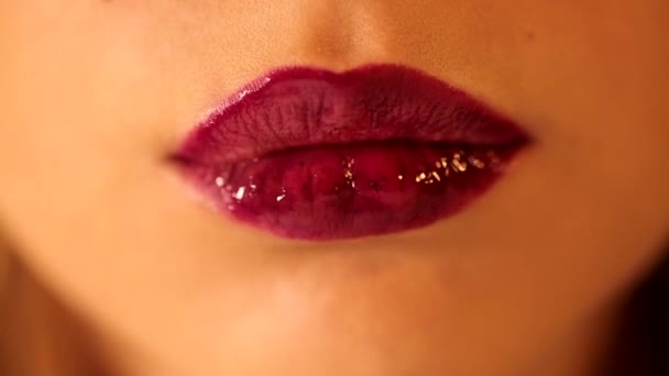 魅力的な女性舌なめる彼女の唇ともに明るい深い赤梅ベリー光沢のある口紅tint lipglosseでクローズアップショット - 映像、動画