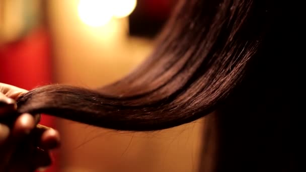 Zblízka pohled na ženské kadeřnice holič ruční otáčení krásné narovnané čokoládové brunetky tmavé barvy lesklé vlasy - Záběry, video