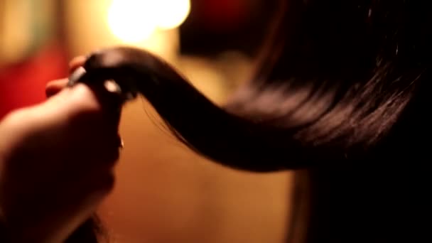 Zblízka pohled na ženu kadeřník holič ruční otáčení krásné narovnané čokoládové brunetky tmavé barvy lesklé vlasy - Záběry, video