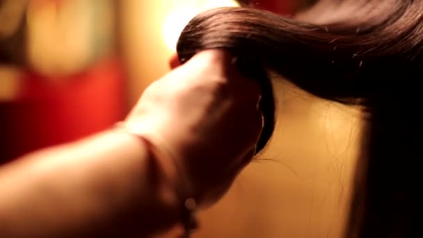 Žena kadeřník holič ruka rotující krásné narovnané čokoládové brunetky tmavé barvy lesklé vlasy v zblízka záběr - Záběry, video