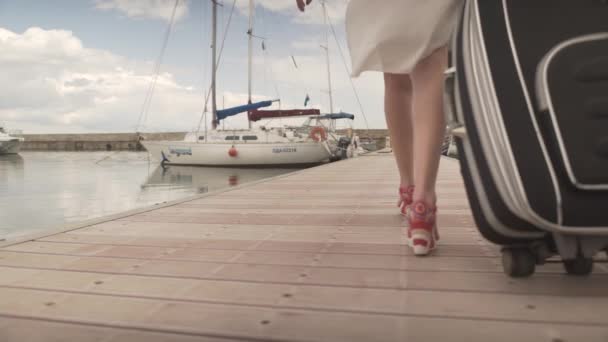 Fit aantrekkelijke jonge vrouw op hoge hakken terug te draaien met zware bagage lopen op houten brug in jacht boot haven - Video