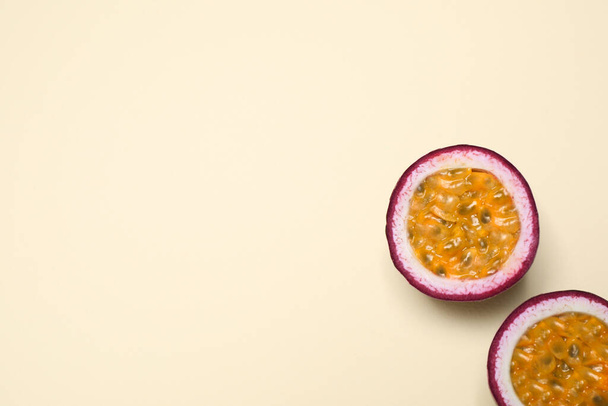 Halves of fresh ripe passion fruit (maracuya) on beige background, flat lay. Space for text - Fotó, kép