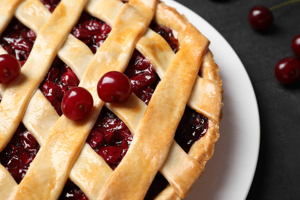 Delicious pie with cherries on black table, closeup - Фото, изображение