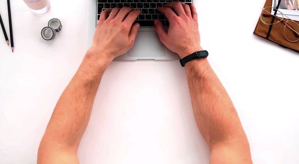 A top photo of the arms of a man who is writing on a keyboard - Photo, Image