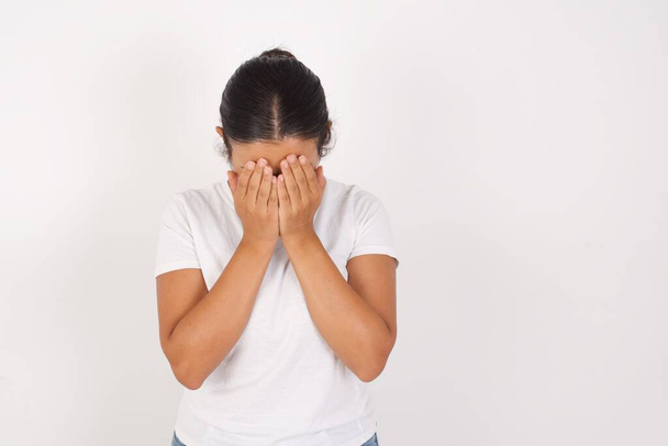 Young arab woman wearing medical mask standing over isolated white background covering her face with her hands, being devastated and crying. Sad concept - Photo, Image
