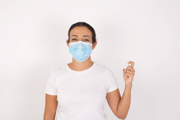 jovem árabe mulher vestindo médico máscara de pé sobre isolado branco fundo apontando para cima com dedos número nove no chinês língua de sinais jiu - Foto, Imagem