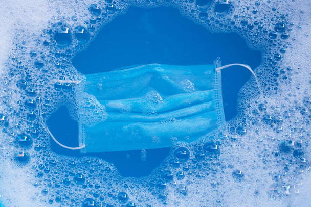 Máscara médica protectora empapar en polvo detergente disolución de agua antes de lavar. Concepto de protección del coronavirus de la higiene (Covid-19). Vista superior - Foto, imagen