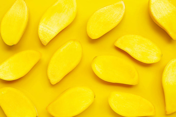 Tropik meyve, sarı arka planda mango dilimleri. Üst görünüm - Fotoğraf, Görsel