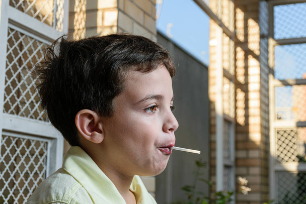 7-vuotias brasilialainen lapsi valokuvaussessiossa päiväkodissa aurinkoisena iltapäivänä. Syöminen tikkari ja valkoinen suklaa. - Valokuva, kuva