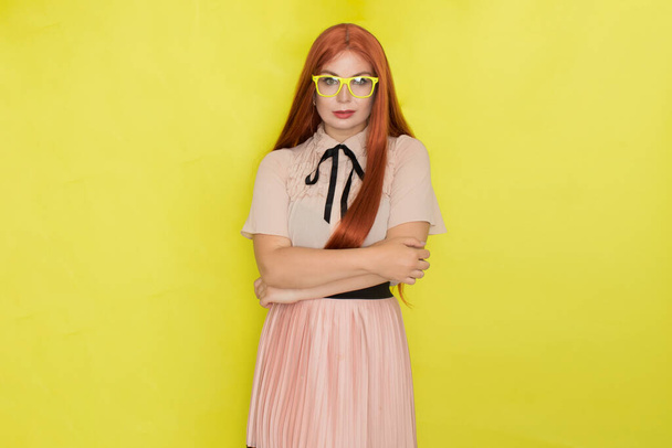 Red haired woman with glasses and office clothing over yellow background, studio, style - Фото, зображення