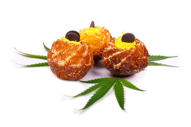 productos frescos dulces horneados con marihuana, tres cupcakes con hojas de plantas de cannabis aisladas sobre fondo blanco, dulces, postres - Foto, Imagen