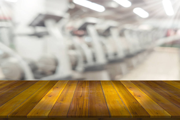 Empty wooden board space platform with blur fitness gym equipment background - Photo, Image