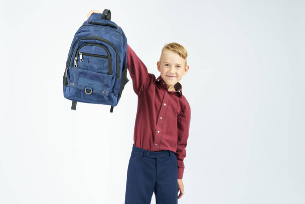 A schoolboy holds a schoolbag lifting it up. Education concept - Zdjęcie, obraz