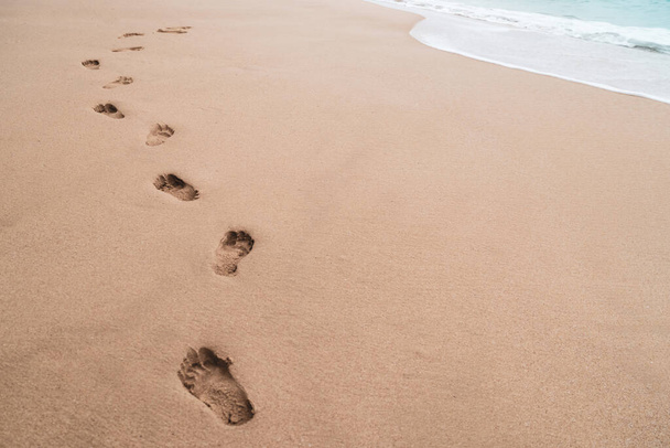 コピースペースと砂の夏の熱帯のビーチの背景に人間の足跡. - 写真・画像