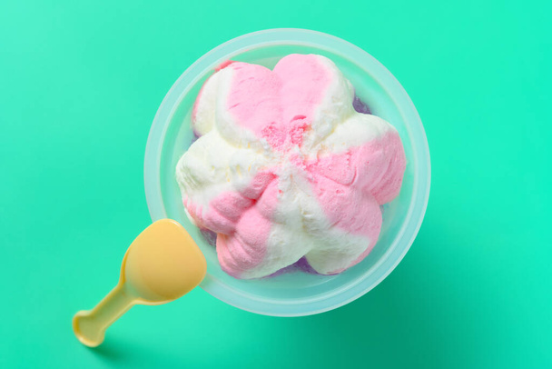 arriba ver taza de helado sabor fresa con una cuchara sobre fondo verde - Foto, imagen