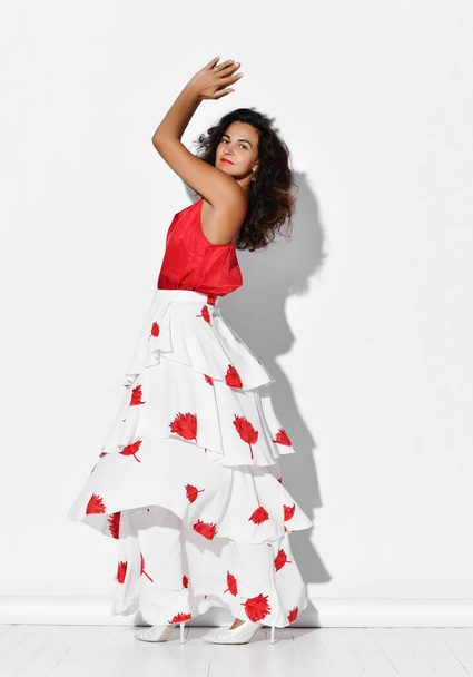 Gorgeous smiling woman hispanic dancer wearing red white gown with flower print dances Carmen flamenco clapping hands up - Foto, Imagem