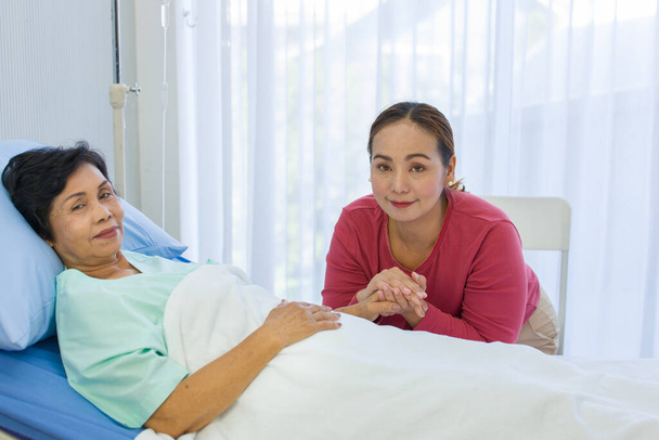 The lovely daughter comes to visit the sick mother while her mom is recuperating at the hospital. Elderly health care concept. - Photo, Image