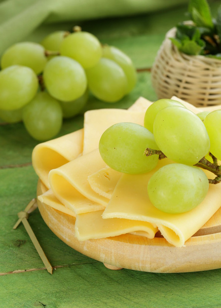 Cheese served on a wooden board with green grapes - Foto, immagini