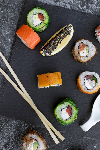 Sushi nastaveno na šedé betonové pozadí. Duhová sushi rolka, uramaki, hosomaki a nigiri. - Fotografie, Obrázek