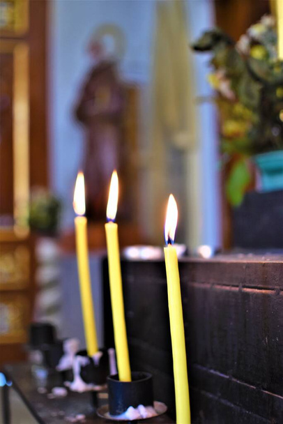 Gyújtott sárga gyertyák egy imaoltáron egy templomban. - Fotó, kép