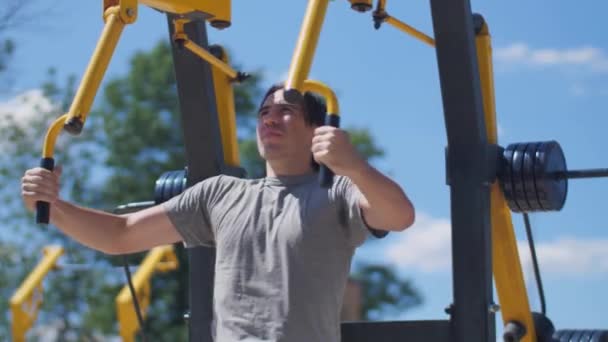 Mann mit langen Haaren trainiert Brustmuskulatur an Fliegenmaschine - Filmmaterial, Video