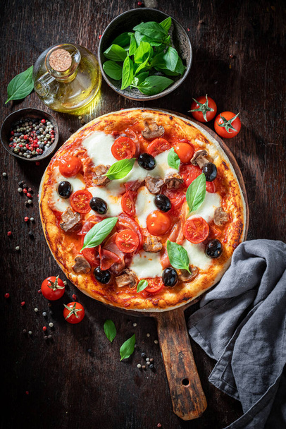 Delicious pizza Capricciosa made of tomatoes, cheese, olives and ham on wooden table - Foto, Bild