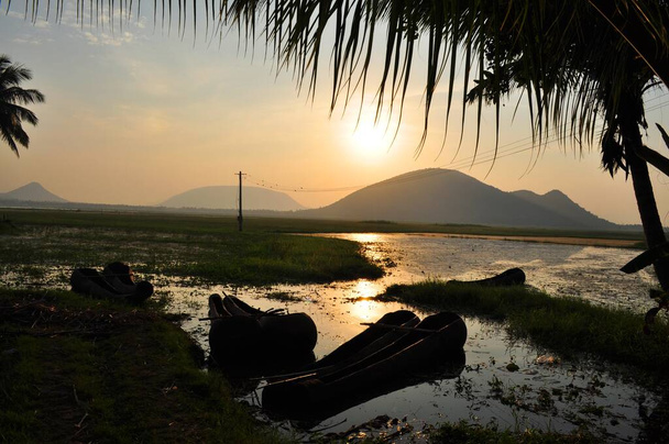Ainutlaatuinen kaivettu veneet makaavat joutilaana massiivinen järvi auringonlaskun aikana Visakhapatnam, Intia. - Valokuva, kuva