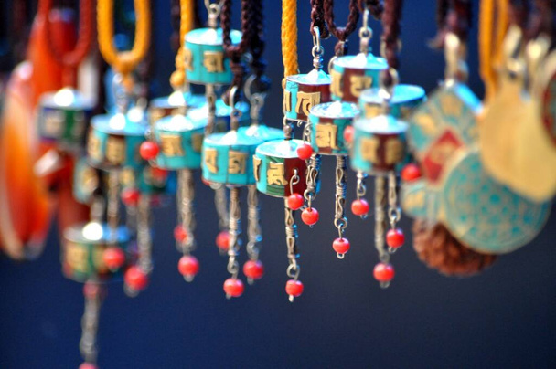 Miniature replicas of Buddhist prayer wheels for use as pendants or earrings hang on display on the streets of Dharamsala, India. - Photo, Image