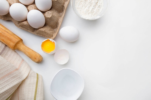 Pişirme malzemeleri un yumurtaları yuvarlanan iğne ve beyaz arka planda mutfak tekstili. Kurabiye ya da kek tarifi maketi. - Fotoğraf, Görsel