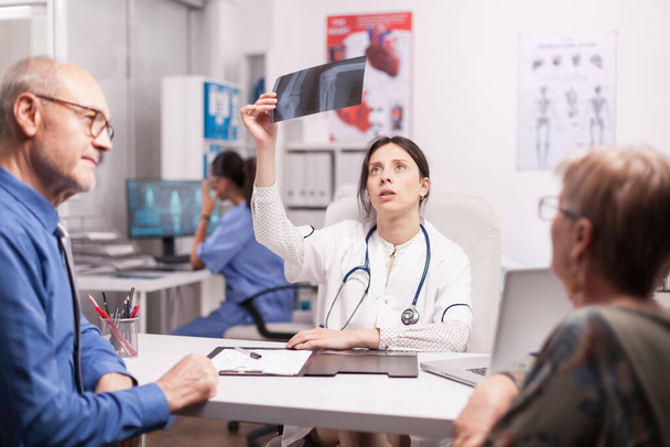 Женщина-врач смотрит на рентген пациента - Фото, изображение