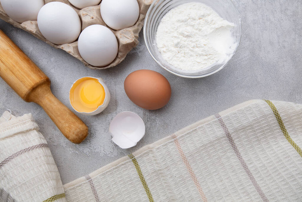 Składniki do pieczenia mąki jaja toczenia pin i tekstylia kuchenne na szarym tle betonu. Ciasteczko lub ciasto makieta przepis - Zdjęcie, obraz