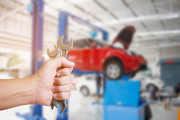 Araba tamircisi araba tamirhanesinde İngiliz anahtarı tutuyor. - Fotoğraf, Görsel