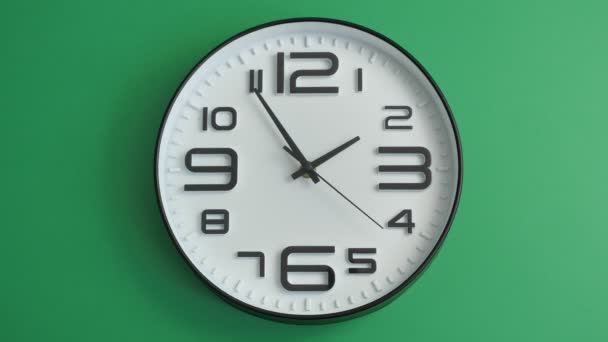 Reloj de oficina blanco único colgando sobre fondo verde - Imágenes, Vídeo