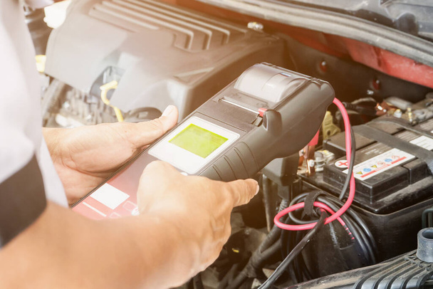 mekaanikko käyttää volttimittari tarkistaa jännite auton akun auton huoltokeskuksessa  - Valokuva, kuva