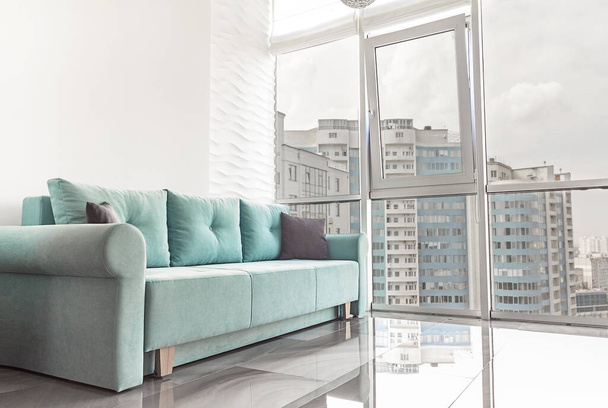современная квартира в светлых тонах. Зеленый диван и большие панорамные окна с видом на внутренний двор Париж июнь 2020 - Фото, изображение