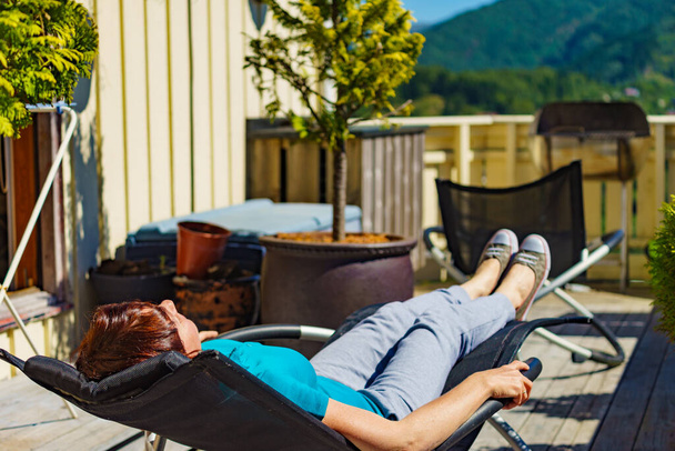 Relax in the sun. Adult woman relaxing resting in deck chair outdoor on veranda. Holiday cottage. - Foto, immagini