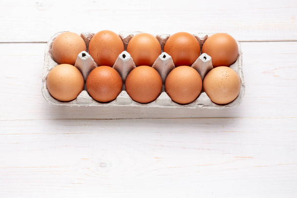 farm red chicken eggs in a cardboard tray on a wooden background. place for tex - Φωτογραφία, εικόνα