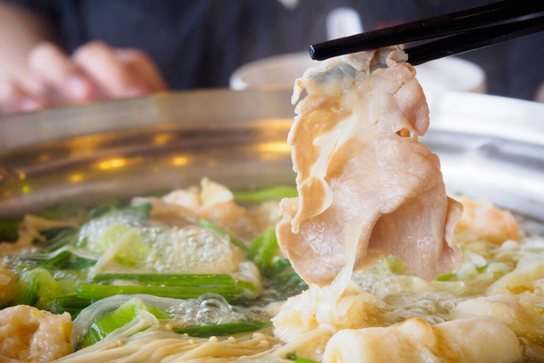 Sukiyaki oder Shabu Shabu Schweinefleisch in Stäbchen über heißen Topf schneiden - Foto, Bild