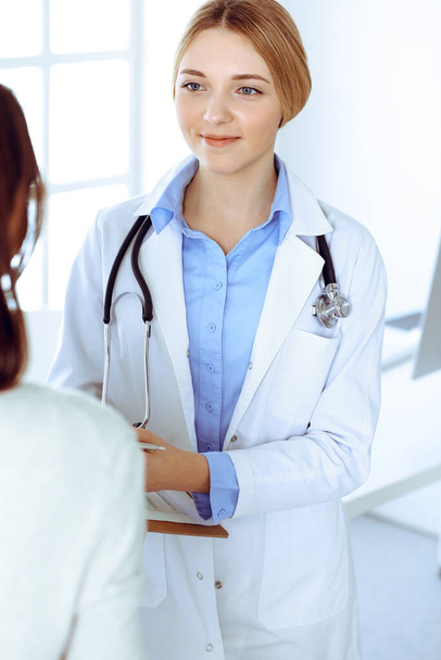 Young woman doctor and patient at medical examination at hospital office. Blue color blouse of therapist looks good. Medicine and healthcare concept - Foto, Imagem