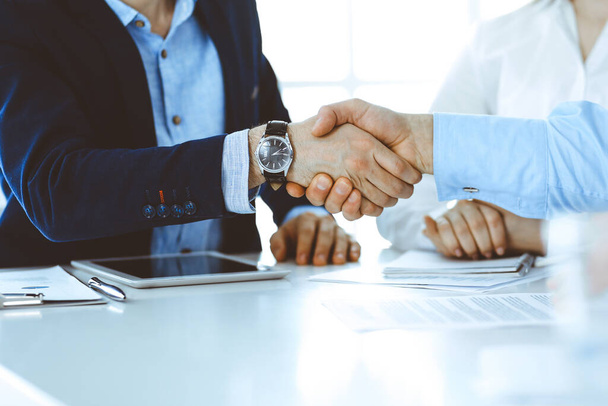 Business people shaking hands at meeting or negotiation, close-up. Group of unknown businessmen and women in modern office. Teamwork, partnership and handshake concept, toned picture - Foto, imagen