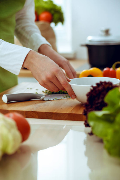 Ismeretlen emberi kéz főz a konyhában. A nőt lefoglalja a zöldséges saláta. Egészséges ételek és vegetáriánus ételek koncepciója - Fotó, kép