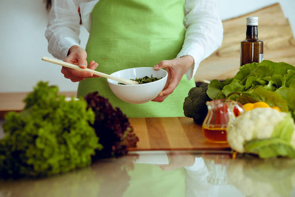 Невідомі людські руки готують на кухні. Жінка зайнята овочевим салатом. Концепція здорової їжі та вегетаріанської їжі
 - Фото, зображення